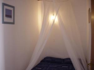 una camera da letto con letto e tende bianche di Lovely CottageAurora with Wi-fi and Private-pool a Corralejo Altre 17 foto