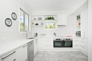 a white kitchen with white cabinets and a window at Sunseeker Views Nelson in Nelson