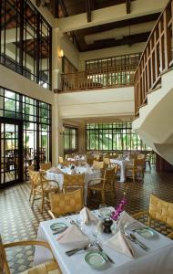 a restaurant with white tables and chairs and windows at Avillion Port Dickson in Port Dickson