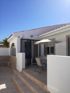 uma casa branca com um pátio com um guarda-chuva em 2 bedroom newly renovated bungalow close to bars & restaurants em Los Alcázares