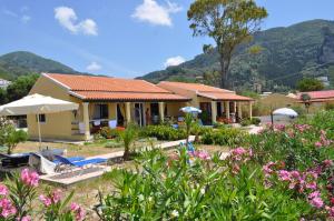 a house with a garden and flowers in front of it at Beachfront Vacation Home eftichia in Agios Gordios