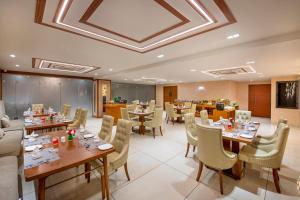a restaurant with tables and chairs in a room at SK Lords Inn Ahmedabad in Ahmedabad