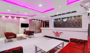 a waiting room at a salon with red chairs and pink lighting at Treebo Trend Orion Sapphire in Ballygunge