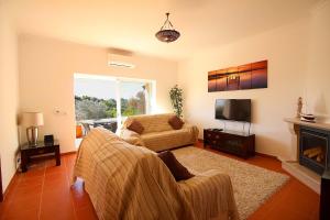 een woonkamer met een bank en een televisie bij Townhouse Mia Panoramic views Communal Pool in Carvoeiro