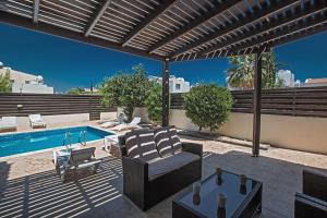 a patio with a couch and a swimming pool at Villa Protaras Eos Modern 3BDR Protaras Villa with Pool Short Walk to all beachresort centre in Protaras
