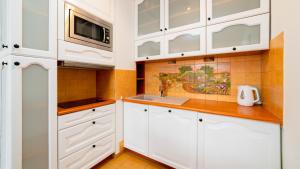 kuchnia z białymi szafkami i mikrofalówką w obiekcie Apartamenty Sun & Snow Osiedle Podgórze w Szklarskiej Porębie