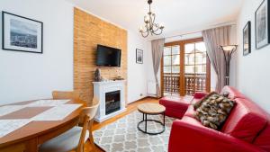 salon z czerwoną kanapą i stołem w obiekcie Apartamenty Sun & Snow Osiedle Podgórze w Szklarskiej Porębie