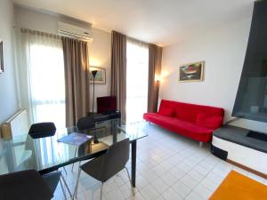 a living room with a red couch and a glass table at Appartamenti Leonardo in Brescia