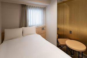 a bedroom with a bed and a table and a window at EN HOTEL Hakata in Fukuoka +59 photos