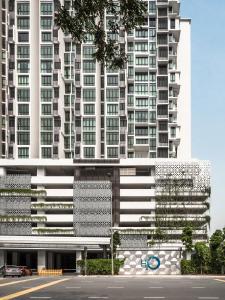 un alto edificio bianco con un parcheggio davanti di H20 Residence Ara Damansara by Airhost a Petaling Jaya
