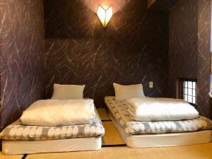 two beds in a room with a black wall at Hostel Yume-Nomad Kobe in Kobe