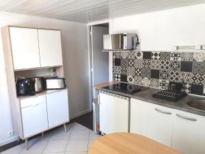 a kitchen with white cabinets and black and white tiles at JungLH by Beds76 in Le Havre