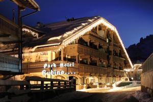 a large building with lights on it in the snow at Hotel Rubino Deluxe in Campitello di Fassa