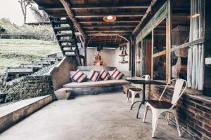 un porche con banco, mesa y sillas en Batukaru Coffee Estate, en Tabanan