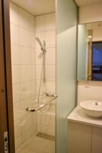 a shower with a glass door next to a sink at Altitude Nozawa in Nozawa Onsen