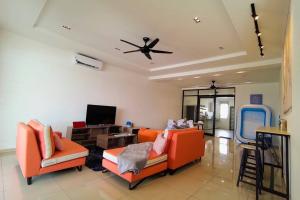 a living room with two orange chairs and a ceiling fan at The Pallet house @ Bandar Sri Sendayan (Seremban) in Kampong Gadong Jaya