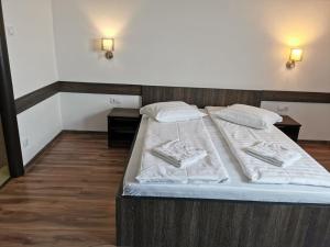 a bed with white sheets and pillows on it at Hotel Tranzit in Odorheiu Secuiesc