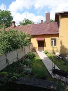 una casa amarilla con una valla y un patio en Park House en Rivne
