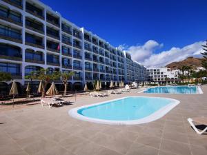 un gran hotel con piscina frente a un edificio en Riviera Peace en Mogán