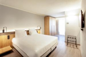 Un dormitorio con una gran cama blanca y una ventana en Palazzo Le Poste - Suite and Apartments en Parma