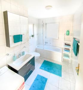 - une salle de bains blanche avec des tapis bleus dans l'établissement Frieda´s Ostseetraum, à Börgerende-Rethwisch