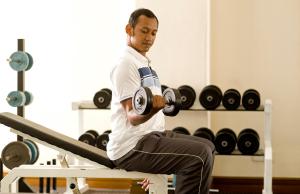 a man sitting on a bench lifting weights at Avillion Admiral Cove in Port Dickson