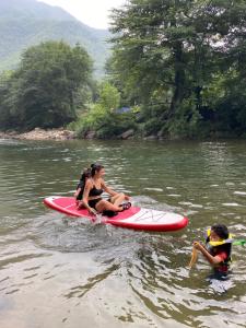 two women are sitting on a paddle board in the water at 安吉 小森林 Little Forest Anji in Anji