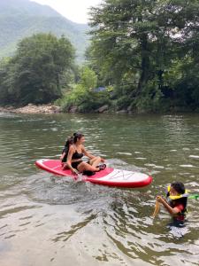 Dos mujeres están sentadas en una tabla de paddle en el agua en 安吉 小森林 Little Forest Anji, en Anji