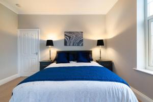 a bedroom with a large bed with blue pillows at Modern Living 2 Bedroom Apartment South Wilmslow in Wilmslow