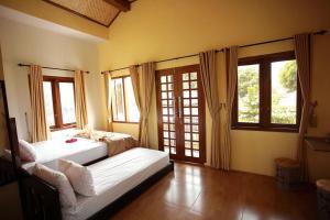 a bedroom with two beds in a room with windows at Grya Pyramyt in Banyuwangi