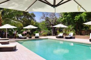 a swimming pool with chairs and umbrellas at Searenity Beach Villa in Diani Beach