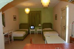 a room with two beds and a tv in it at Perla Apartments in Agia Pelagia
