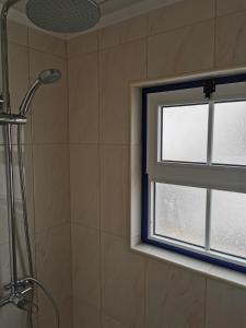 uma casa de banho com um chuveiro e uma janela em Casa da Eira Velha em Fajã do Ouvidor