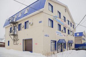 a white building with a blue roof in the snow at Hotel Mir in Izhevsk