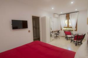 1 dormitorio con cama roja, mesa y sillas en Hostal Casa Arco Iris (Playa), en Los Caños de Meca