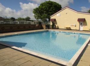 a large blue swimming pool next to a building at cabin zest in Sandown