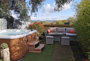 un patio trasero con bañera de hidromasaje, mesa y sillas en The Base Vegan Retreat Animal Sanctuary en Bristol