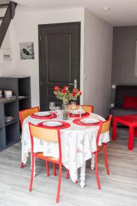 mesa de comedor con sillas rojas y mantel blanco en La Tanière, en Brette-les-Pins