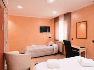 a hotel room with two beds and a desk at Hotel Los Toreros in Tordesillas
