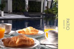 a table with two plates of croissants and orange juice at Pool Access 2 BDR Stylish Condo in Kamala Beach