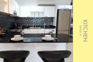 una cocina con armarios en blanco y negro y 2 taburetes en Pool Access 2 BDR Stylish Condo en Kamala Beach
