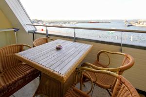 a table and chairs on a balcony with a view of the water at Hafenhäuser Wiek FeWo 15 - Balkon, Meerblick in Wiek auf Rügen 