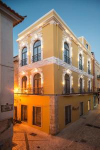 um edifício amarelo com janelas e varandas numa rua em Day Off Suite&Hostel em Setúbal