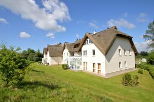 a large white house with a gambrel roof at strandnah mit Balkon, gratis Nutzung vom AHOI Erlebnisbad und Sauna in Sellin - Strandhaus Mönchgut FeWo13 in Lobbe