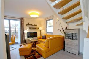 a living room with a yellow couch and a tv at Ferienhaus Stranddistel Haus - Terrasse, Garten, Sauna in Klein Gelm