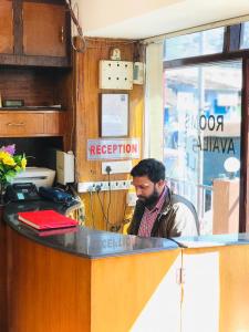 um homem sentado ao balcão de um despachante em mystique inn em Ooty