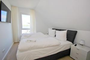1 dormitorio con 1 cama con sábanas blancas y ventana en hafennahes Ferienhaus mit Terrasse und Meerblick - Ferienhaus TimpeTe Steuerbord, en Gager