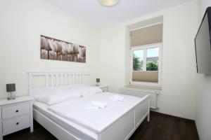 ein weißes Schlafzimmer mit einem weißen Bett und einem Fenster in der Unterkunft Ferienwohnung mit eigener Sauna in zentraler Lage - Kurhaus Nordstrand FeWo 32 in Göhren
