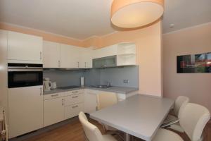 eine Küche mit weißen Schränken und einem Tisch und Stühlen in der Unterkunft strandnah mit Balkon, gratis Nutzung vom AHOI Erlebnisbad und Sauna in Sellin - Strandhaus Mönchgut FeWo12 in Lobbe