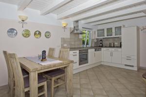 a kitchen with white cabinets and a wooden table and chairs at strandnahe Idylle am Meer, private Badestelle, Strandkorb - Gutshof Ostseeblick in Neuendorf